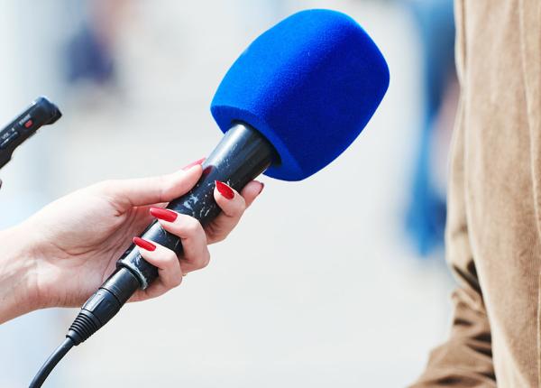 Microphone held in front of person wearing brown jacket.