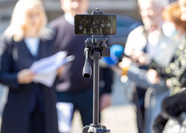 Cellphone on tripod pointed at people standing in background.