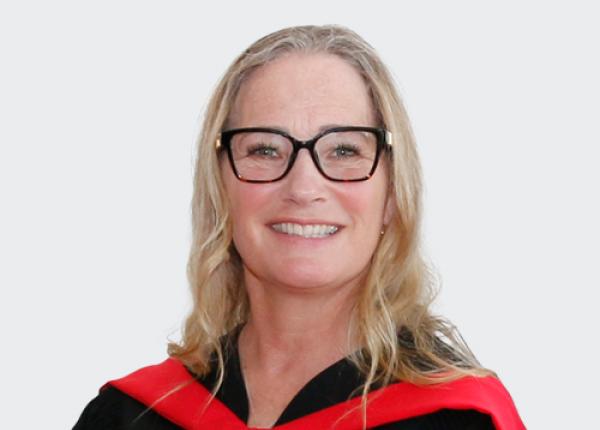 Woman with black-rimmed glasses wearing black convocation gown.