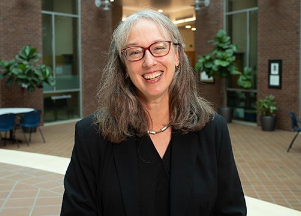 Woman with glasses wearing black jacket and top.