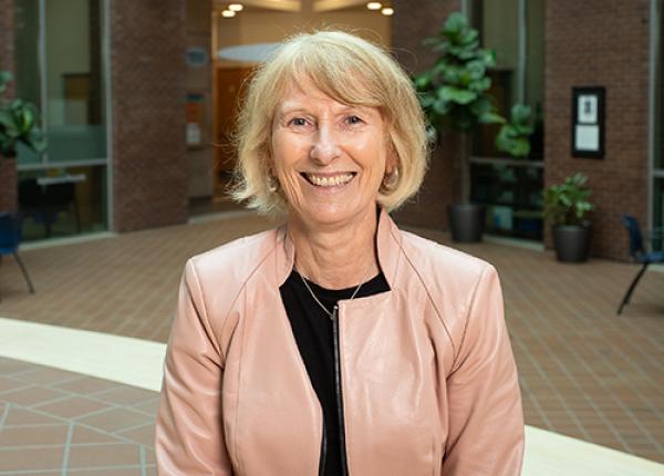 Light-haired woman wearing rose pink jacket and black blouse.