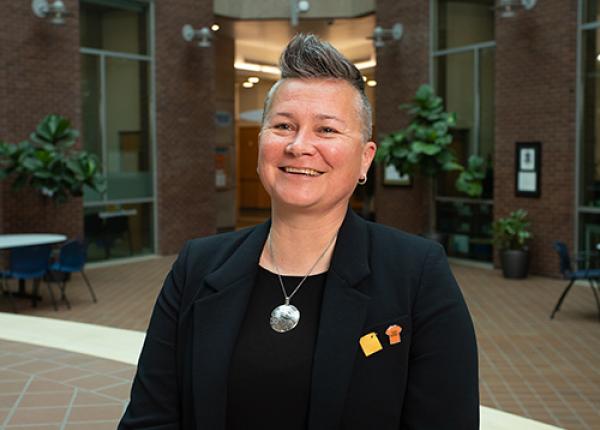 Woman with short hair wearing black jacket and top.