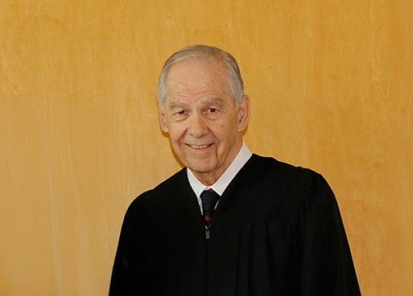 Head and shoulders shot of man in black graduation robe.