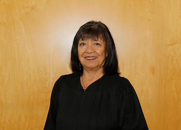 Head and shoulders shot of woman with dark hair in black graduation gown.