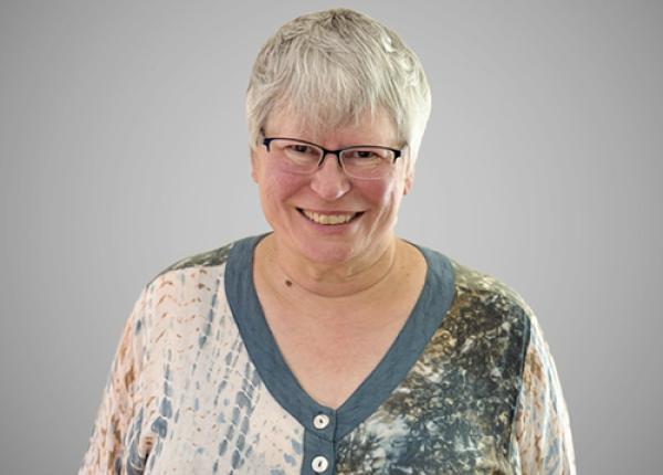 Woman with grey hair wearing glasses.