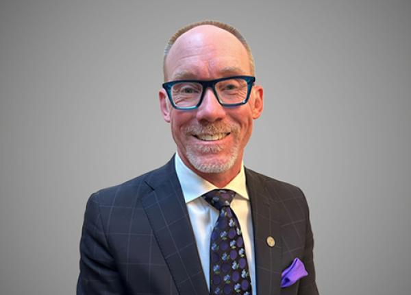 Man with glasses wearing dark suit and tie.