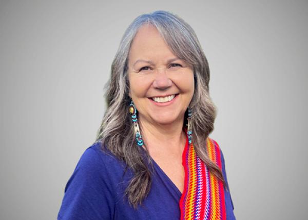Woman wearing dark blue top with red Metis sash over her left shoulder..