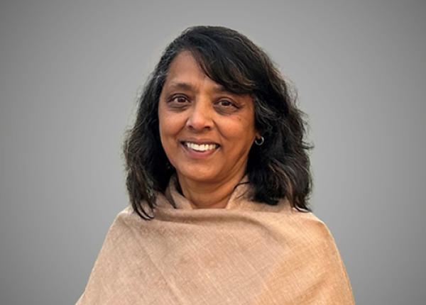 Woman with dark hair wearing beige shawl.